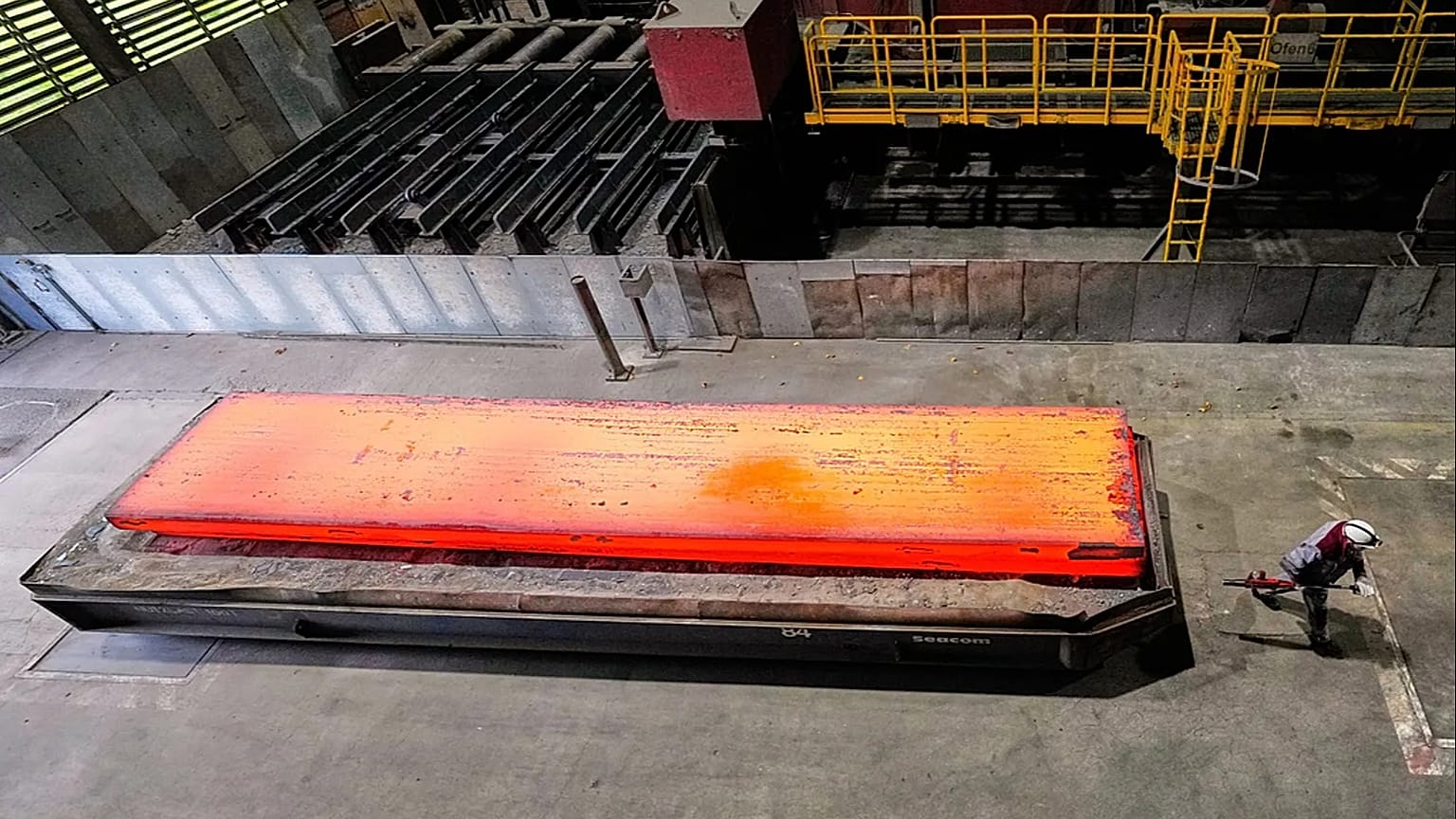 A man walks past a glowing steel plate at the thyssenkrupp steel mill in Duisburg, Germany.