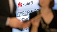 Two people look at their cellphones in front of the Huawei logo during a DigitALL lunch talk in Brussels, Tuesday, May 21, 2019.