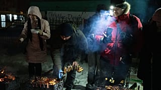 يقوم الناس بالطهي على الشوايات ويتدفؤون خارج مبانيهم متعددة الطوابق خلال انقطاع التيار الكهربائي الناجم عن الغارات الجوية الروسية الأحد 18 يناير 2026. (صورة من وكالة أسوشيتد ب