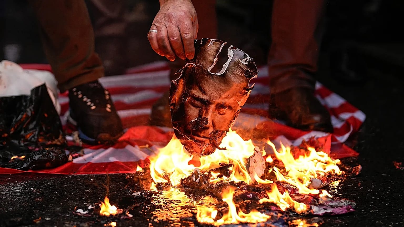 A man burns a photograph of US President Donald Trump during a rally in support of the Iranian government in Istanbul, 18 January, 2026