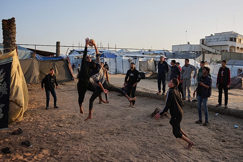 Young Palestinians play volleyball at a tent camp sheltering displaced families in Deir al-Balah, in the central Gaza Strip Tuesday, Jan. 20, 2026.