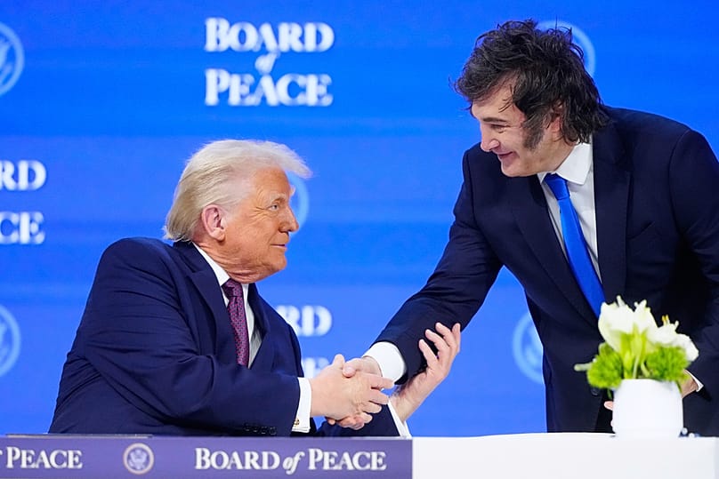 US President Donald Trump shakes hands with Argentinian President Javier Milei, right, during a session on his Board of Peace initiative in Davos, 22 January 2026