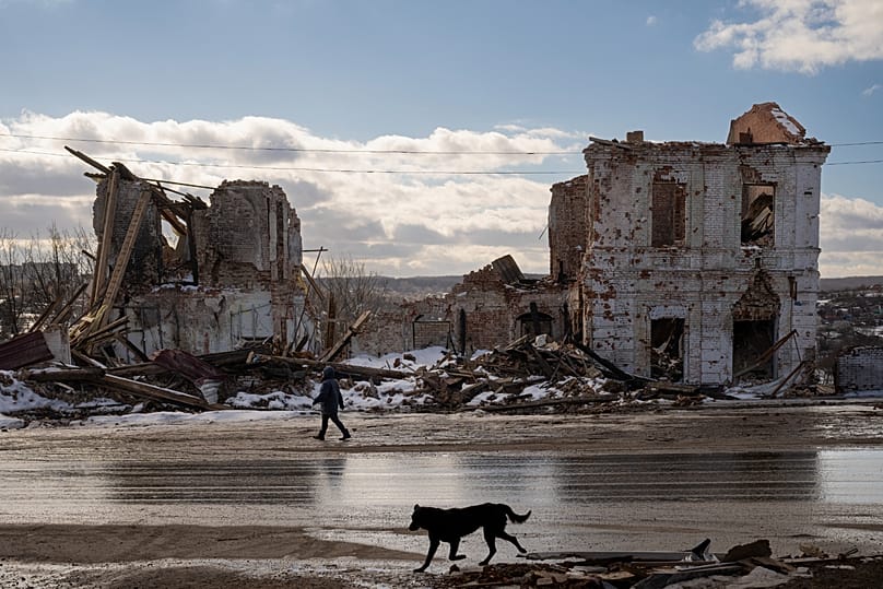 A woman walks by a building destroyed by a Russian strike in Kupiansk, 20 February, 2023