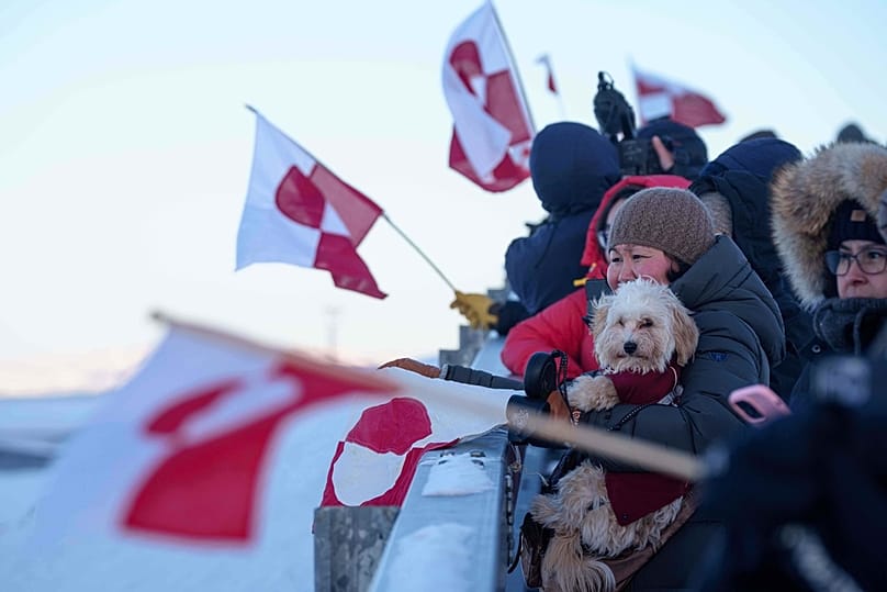 People wave national flags for Greenland Minister for Foreign Affairs and Research Vivian Motzfeldt as she arrives at the airport in Nuuk, 20 January 2026