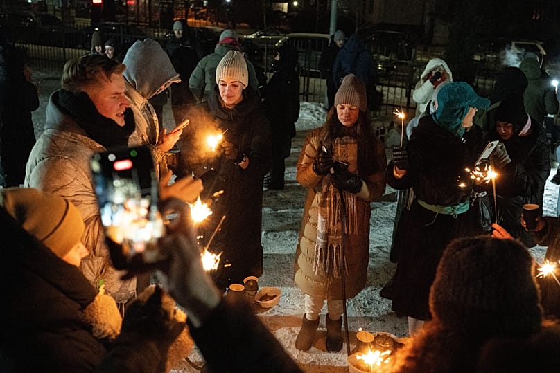 People warm up outside their buildings during a power outage in Kyiv, 18 January, 2026