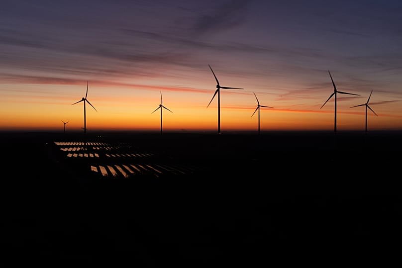 Wind turbines operate as the sun rises at the Klettwitz Nord solar energy park near Klettwitz near Klettwitz, Germany, October 2024.