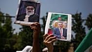 متظاهر يحمل ملصقاً لولي العهد الإيراني المنفي رضا بهلوي (يمين الصورة)، وملصقاً مشوهاً للمرشد الأعلى الإيراني آية الله علي خامنئي، خلال مسيرة دعماً للاحتجاجات المناهضة للحكومة 