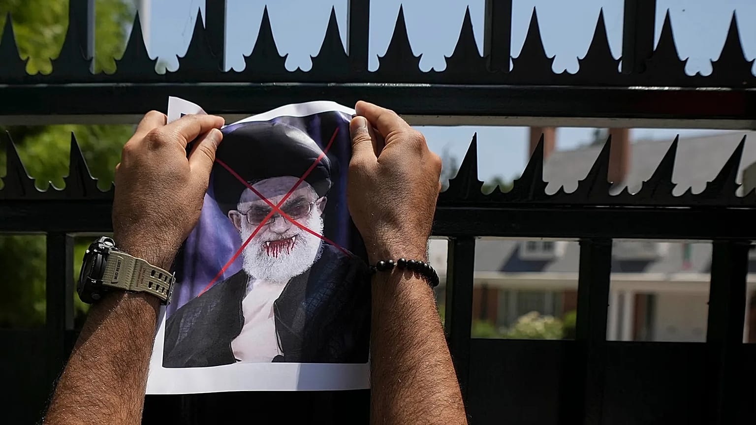 A defaced poster of Ayatollah Ali Khamenei is placed by a demonstrator on a gate of Iran's embassy in Santiago, 20 January, 2026