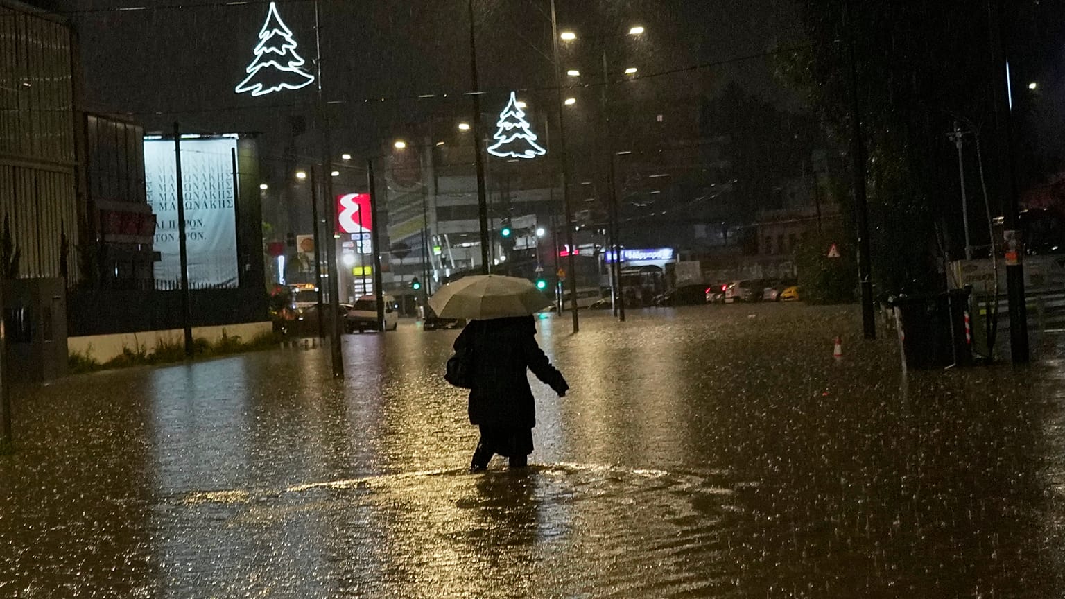 Mulher caminha numa rua inundada durante temporal em Atenas