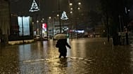 A woman walks on a flooded street during a rainstorm in Athens