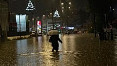Starkregen hat in Athen Straßen überschwemmt. Eine Frau läuft eine überflutete Straße entlang.