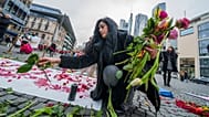 زنی در حال قرار دادن گل در مکانی نمادین برای گرامیداشت جان باختگان اعتراضات ایران در جریان تظاهرات حامیان معرتضان ایرانی در شهر کلن آلمان
