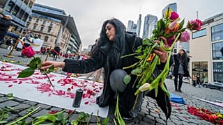 زنی در حال قرار دادن گل در مکانی نمادین برای گرامیداشت جان باختگان اعتراضات ایران در جریان تظاهرات حامیان معرتضان ایرانی در شهر کلن آلمان