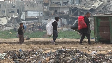 أشخاص يحملون أكياسا تحتوي على مواد جمعوها من النفايات لاستخدامها كوقود لإشعال النار