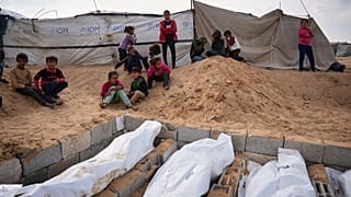 أطفال يشاهدون دفن جثث فلسطينيين مجهولي الهوية، تم إعادتهم من إسرائيل كجزء من اتفاق وقف إطلاق النار، في دير البلح، قطاع غزة