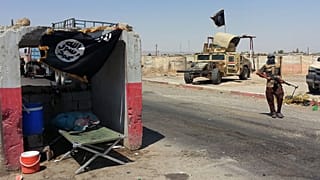 مقاتل متأثر بتنظيم القاعدة يقف بجانب عربة همفي تابعة للجيش العراقي تم الاستيلاء عليها عند نقطة تفتيش خارج مصفاة بيجي