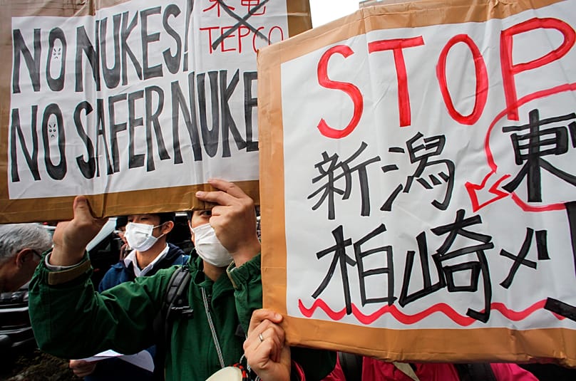 Protesters hold placards during a rally to oppose nuclear power generation held in front of the TEPCO headquarters in Tokyo, 3 April, 2011