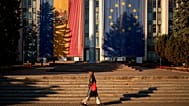 A woman walks in front of a government building decorated with European Union and Moldovan flags in Chișinău, 26 September, 2025