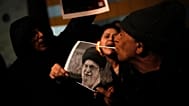 A demonstrator lights a cigarette with a burning poster depicting Supreme Leader Ayatollah Ali Khamenei during a rally in Holon, 14 January, 2026