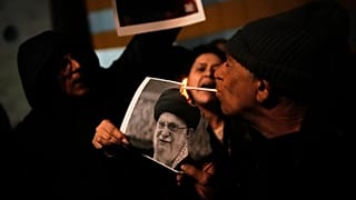 A demonstrator lights a cigarette with a burning poster depicting Supreme Leader Ayatollah Ali Khamenei during a rally in Holon, 14 January, 2026