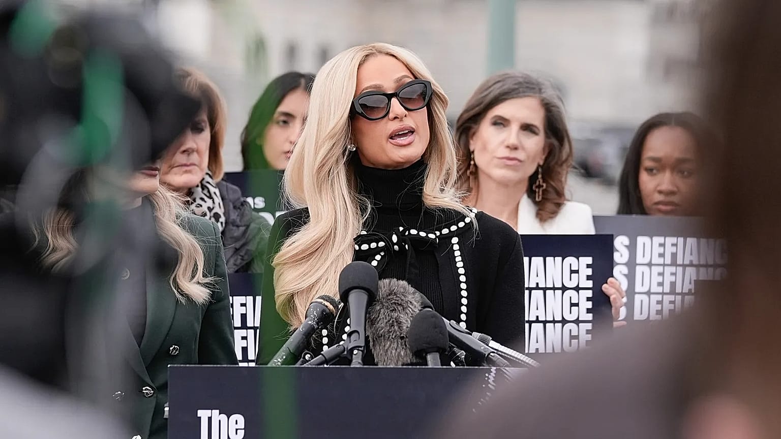 Paris Hilton se dirige a los medios de comunicación junto a varias víctimas