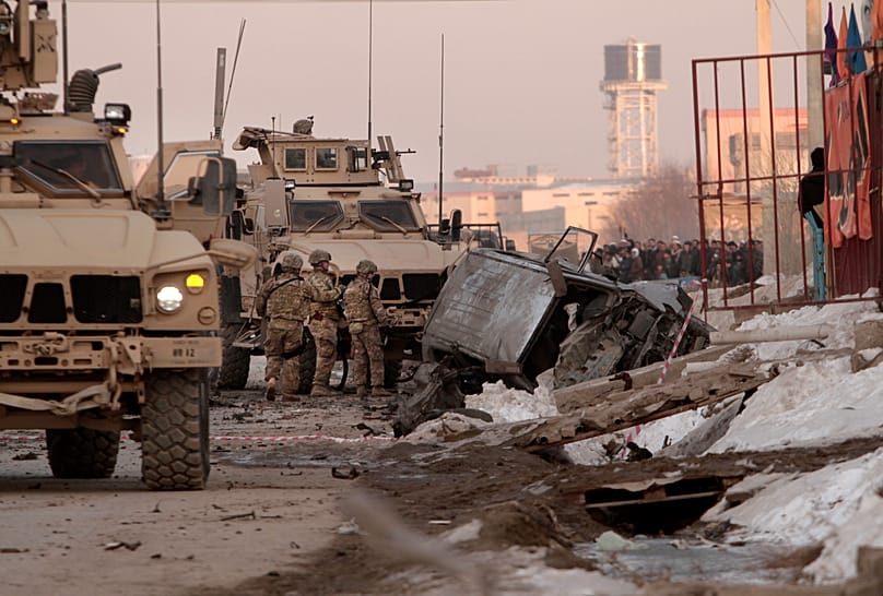 US soldiers and Afghan security forces search the site where a suicide attacker rammed a car bomb into a NATO convoy in Kabul, 10 February, 2014