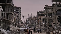 فلسطينيون يسيرون في شارع تحيط به مبانٍ مدمّرة جرّاء العمليات الجوية والبرية الإسرائيلية في خان يونس، جنوب قطاع غزة، الخميس 22 جانفي/يناير 2026. 
