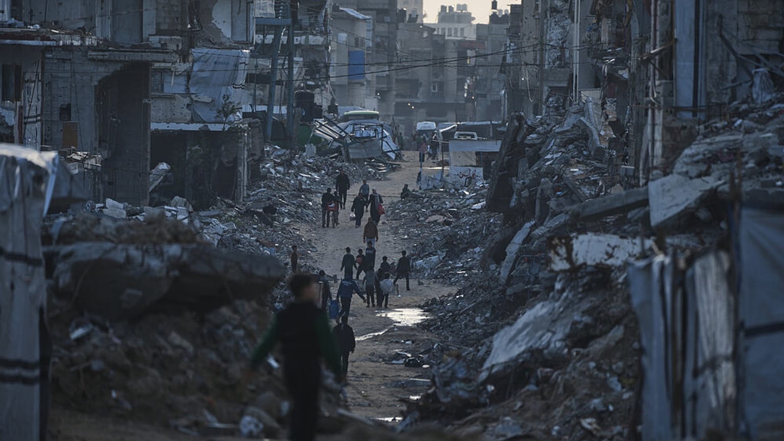 الفلسطينيون يمشون وسط المباني المدمرة جراء العمليات الجوية والبرية الإسرائيلية في مدينة غزة، يوم الخميس 15 يناير 2026. (تصوير: جيهاد الشريف / أسوشيتد برس)