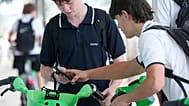 School boys use their phones as they rent bicycles in Sydney, Monday, 8 December, 2025.