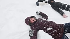 Links im Bild spielt Sadie Eidson im Schnee und lacht. Im Central Park tobt am Sonntag, 25. Januar 2026, ein Wintersturm.