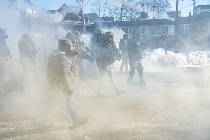 Federal agents walk through a cloud of tear gas deployed against a crowd protesting the fatal shooting of Alex Pretti by agents in Minneapolis, MN, Jan. 24, 2026