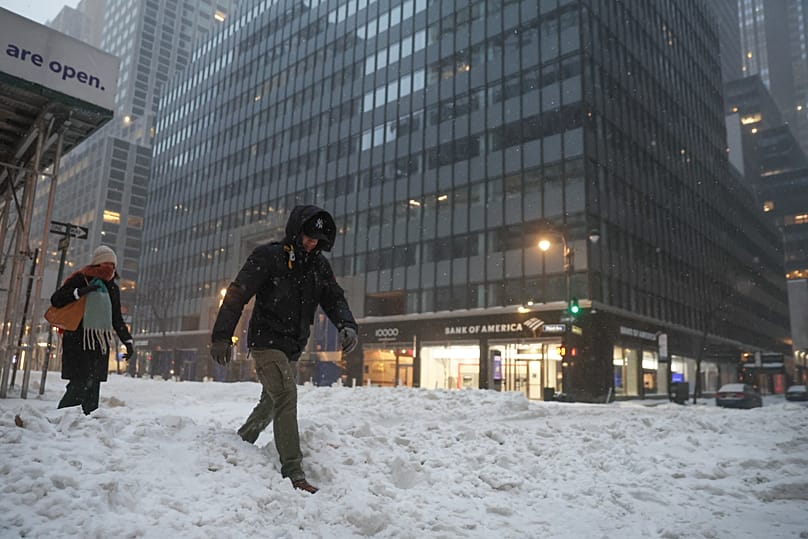 Des piétons traversent la rue pendant une tempête hivernale, dimanche 25 janvier 2026, à New York.