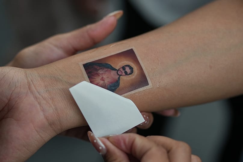 Una persona se pone un tatuaje temporal durante uno de los conciertos de artista.
