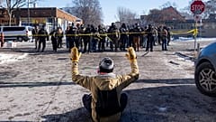 Ein Demonstrant sitzt mit erhobenen Armen auf der Straße vor Bundesbeamten in Minneapolis, Samstag, 24. Januar 2026. (Alex Kormann/Star Tribune via AP)