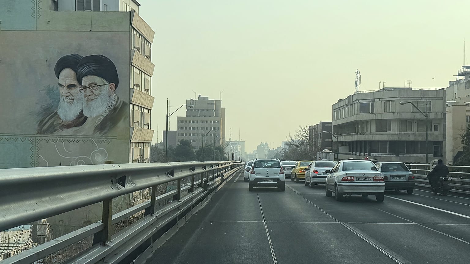 تمر المركبات أمام صورة مؤسس الثورة الإيرانية الراحل آية الله الخميني (يسار) والمرشد الأعلى آية الله علي خامنئي، في وسط مدينة طهران، إيران، الأحد 25 يناير 2026. (صورة من وكالة 
