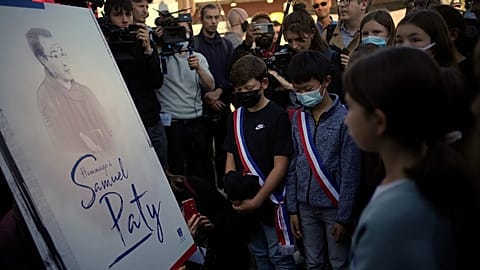 Children stand in front of a drawing of French history and geography teacher Samuel Paty in Conflans Sainte Honorine, 16 October, 2021