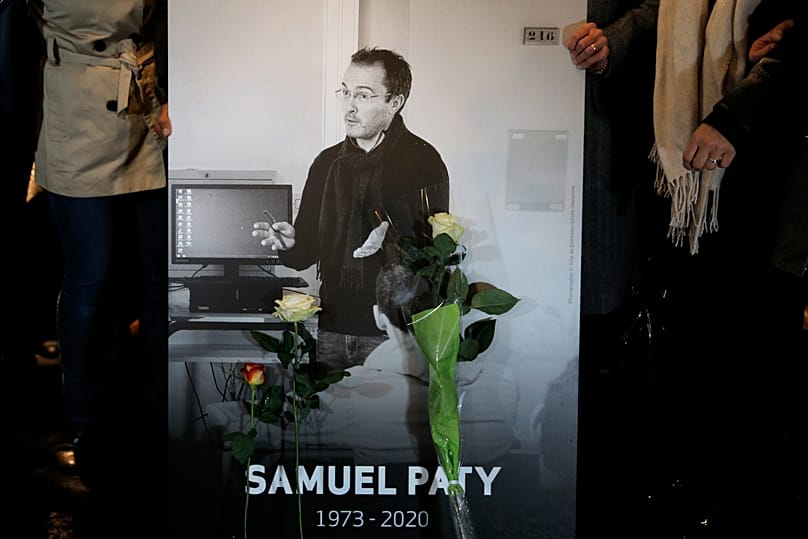 People hold a photo of the history teacher Samuel Paty who was beheaded in Conflans-Sainte-Honorine, 20 October, 2020 