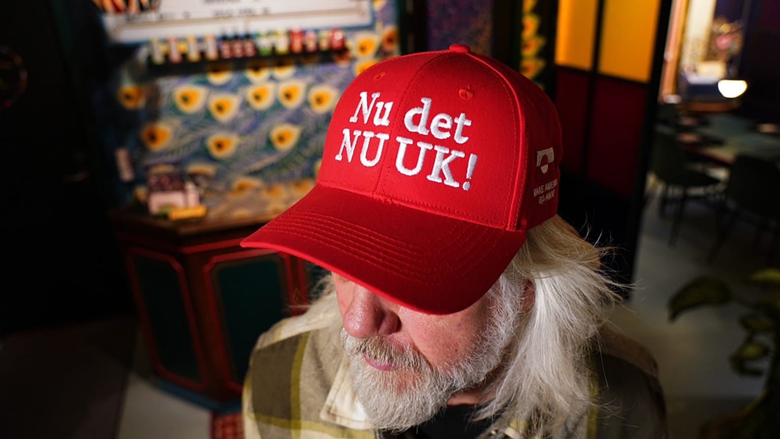 Proprietário de loja usa boné vermelho à venda que ele criou com o slogan «Nu det NUUK!», variação da expressão dinamarquesa «Nu det nok», que significa "Agora, já chega". 
