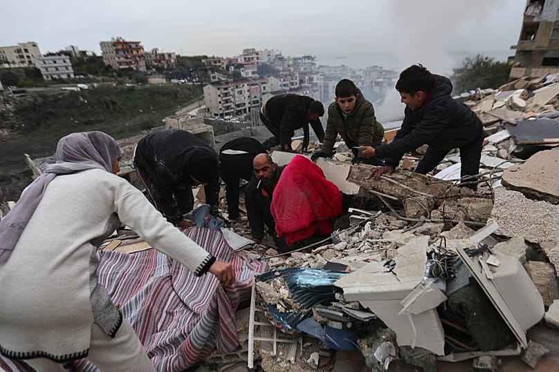 عائلة تجمع ما تبقّى من مقتنياتها من مبنى دمّره قصف إسرائيلي في بلدة قناريت جنوب لبنان، في 22 يناير 2026.
