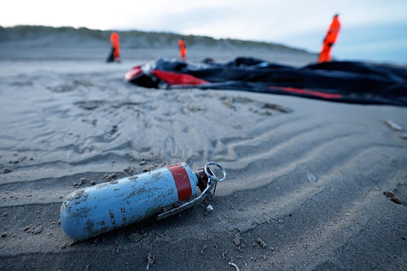 An unexploded tear gas grenade lays on the beach next to an inflatable boat punctured by French police and used by migrants to cross the Channel, 22 December, 2025