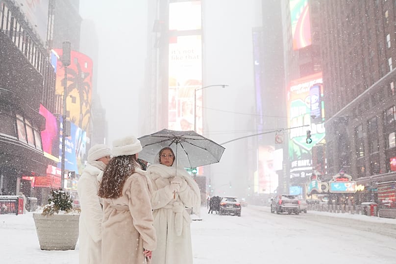 Menschen warten während eines Wintersturms am Sonntag, dem 25. Januar 2026, in New York auf dem Times Square, um die Straße zu überqueren.