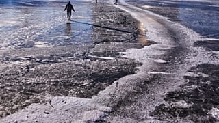 Menschen balancieren an einem kalten Wintertag in Berlin, Deutschland, am Sonntag, dem 11. Januar 2026, über den zugefrorenen Landwehrkanal.