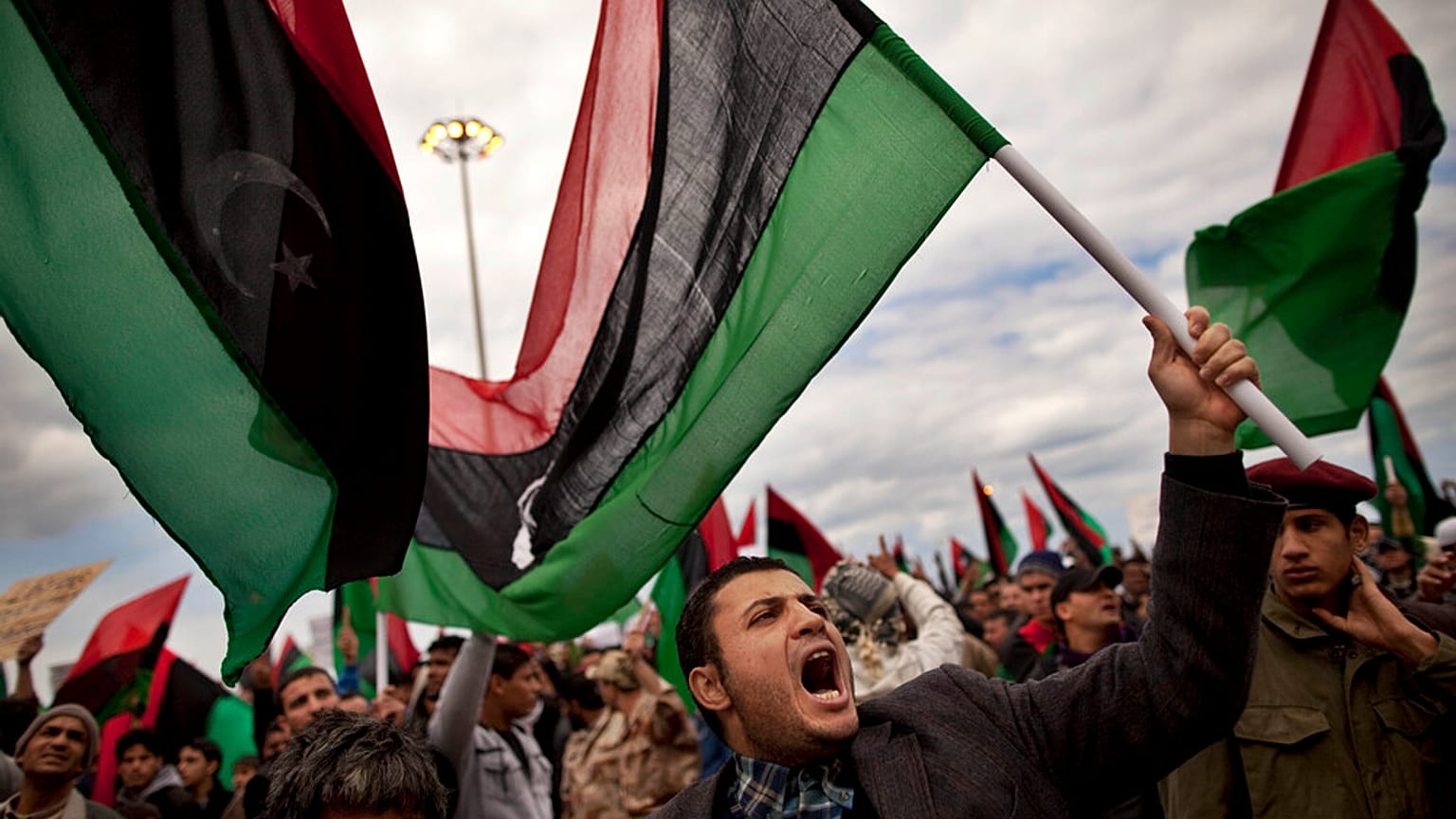 رجال ليبيون، بعضهم يرفع أعلام ليبيا ما قبل القذافي، يهتفون خلال مظاهرة للمطالبة باستقالة الزعيم الليبي معمر القذافي وفرض منطقة حظر جوي، في بنغازي شرق ليبيا