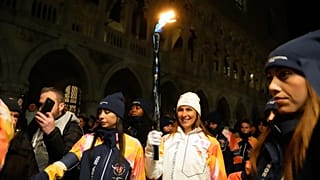 Uma portadora da tocha segura a chama olímpica em Veneza, Itália, quinta-feira, 22 de janeiro de 2026