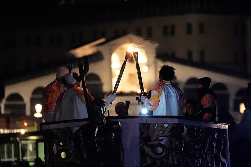 portadores da tocha olímpica levam a chama pelo Grande Canal, em Veneza, Itália, na quinta-feira, 22 de janeiro de 2026.