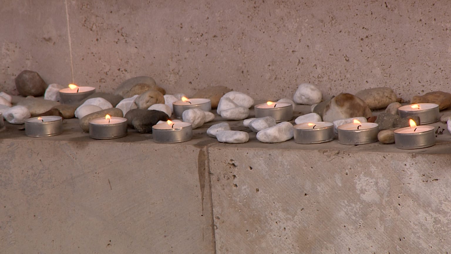 Kövek és mécsesek a Páva utcai központban az áldozatok emlékfalánál 2026. január 27-én 