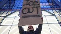 Una manifestante tiene un cartello con la scritta “Fuori l'Ice” durante una protesta a Minneapolis (26 gennaio 2026)