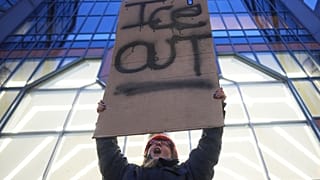 Una manifestante tiene un cartello con la scritta “Fuori l'Ice” durante una protesta a Minneapolis (26 gennaio 2026)