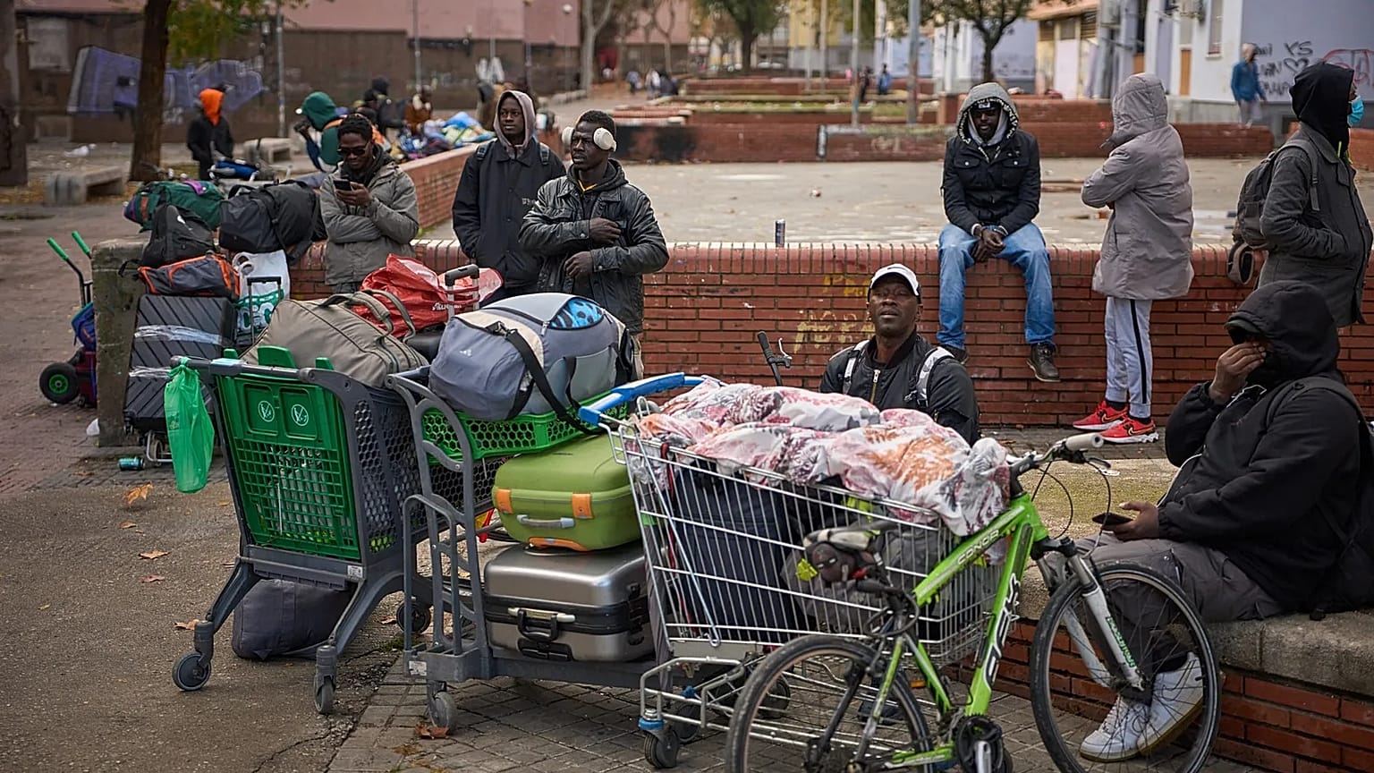 Migrants sit together with their belongings after being evicted by police from an abandoned school where they had been living in Badalona, 17 December, 2025