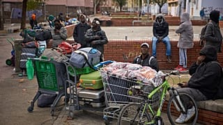 Migrants sit together with their belongings after being evicted by police from an abandoned school where they had been living in Badalona, 17 December, 2025